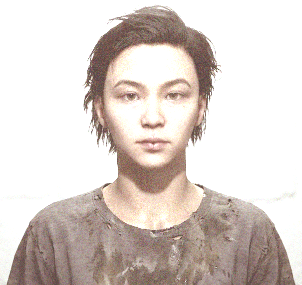 A PORTRAIT OF ROBIN, A YOUNG ADULT WITH SHORT HAIR AND A NEUTRAL EXPRESSION.